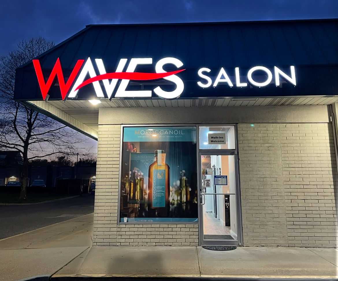 Waves Salon entrance at night with Moroccanoil poster and welcoming lights.